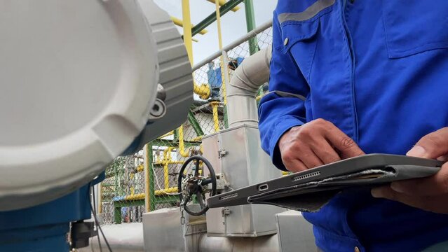 Production engineers inspect industrial equipment at pipeline at factory. Referent holding a tablet with a design sheet. Concept of industry and technology