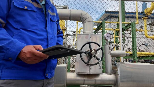 Production engineers inspect industrial equipment at pipeline at factory. Referent holding a tablet with a design sheet. Concept of industry and technology