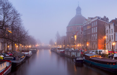 Fototapeta premium Beautiful old houses on the city waterfront of Amsterdam at sunset.