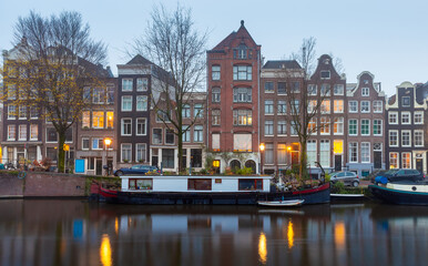 Naklejka premium Beautiful old houses on the city waterfront of Amsterdam at sunset.