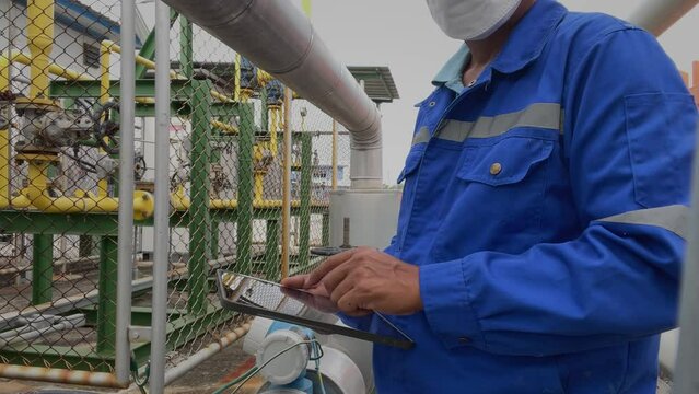Production engineers inspect industrial equipment at pipeline at factory. Referent holding a tablet with a design sheet. Concept of industry and technology