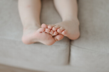Fototapeta na wymiar child bare little feet close-up indoors. child sitting barefoot