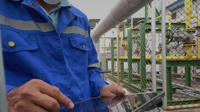 Production engineers inspect industrial equipment at pipeline at factory. Referent holding a tablet with a design sheet. Concept of industry and technology