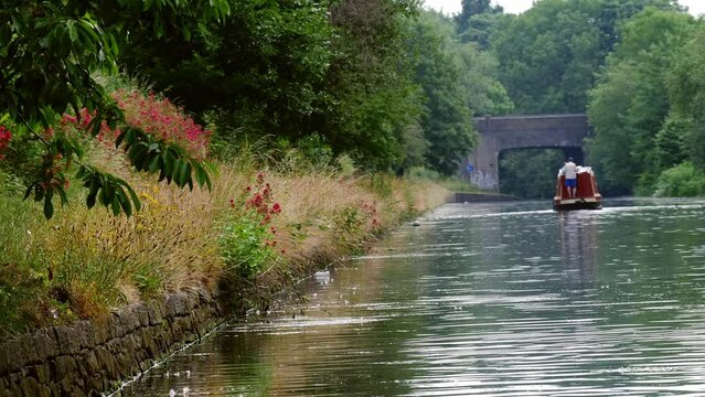 Barge on canal waterway in England on summer day wide establishing