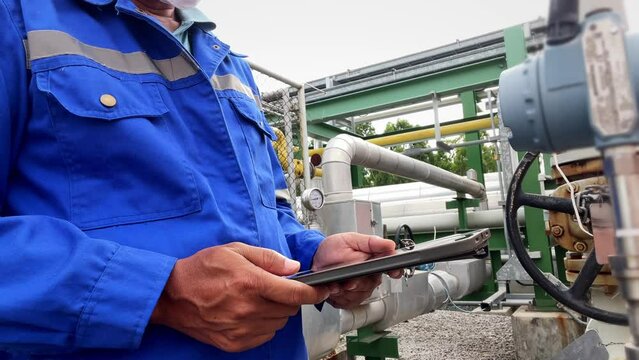 Production engineers inspect industrial equipment at pipeline at factory. Referent holding a tablet with a design sheet. Concept of industry and technology
