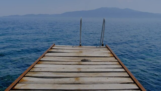 Old rusty pier swimming platform in Assos - Canakkale located at Aegean coasts of Turkey. Midilli - Lesbos Island in the background.