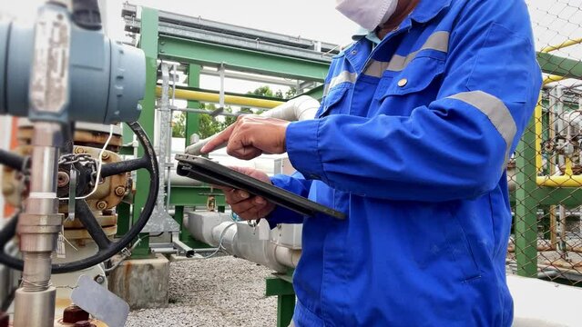Production engineers inspect industrial equipment at pipeline at factory. Referent holding a tablet with a design sheet. Concept of industry and technology