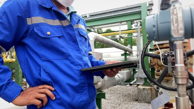 Production engineers inspect industrial equipment at pipeline at factory. Referent holding a tablet with a design sheet. Concept of industry and technology