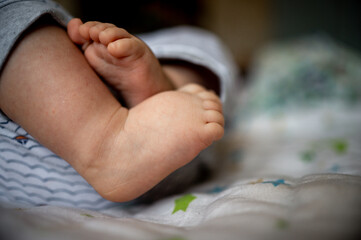the legs of a newborn baby who is lying on the bed at home
