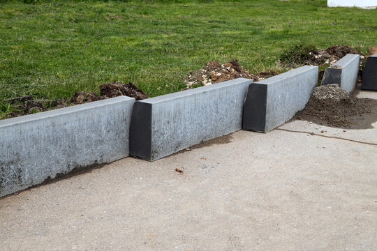 New curbs stand at the edge of the sidewalk. Preparing to repair road