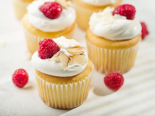 Close-up. Appetizing muffins with cream, decorated with raspberries and almonds on a white background. Cookbook, culinary blog, restaurant and home cooking.
