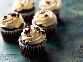 Lots of chocolate buttercream muffins garnished with grated dark chocolate on a green marble background. Festive treat, sweet food. Birthday, holiday, banquet, picnic.