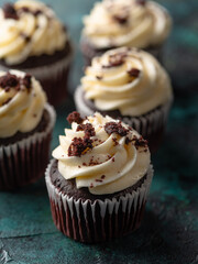 Close-up. Chocolate muffins with whipped cream, decorated with dark chocolate crumbs on a green background. Restaurant, hotel, cafe, confectionery, supermarket. Advertising, banner.
