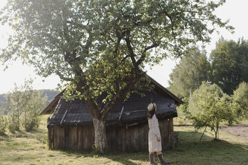 romantic portrait of a young woman in straw hat and beautiful dress in the countryside in summer