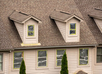 Masking tape holding plastic covering in place on windows prior to spraying paint on home