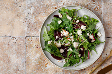Beet salad with mix lettuce leaves salad with feta cheese, nuts in a plate. Fresh green snack. Keto...