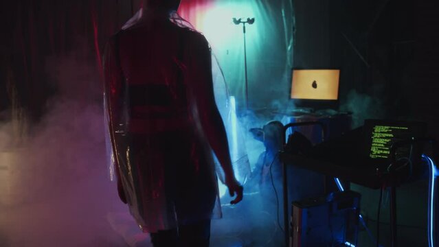 Medium long of Cyberpunk girl in plastic coat moving trolley with computer in hideout with neon lights and smoke