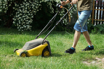 mowing the grass by a person with an electric mower