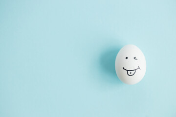 Fototapeta na wymiar Egg with funny face on blue background