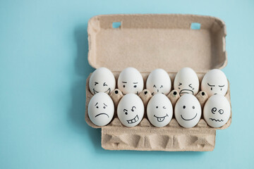 Eggs with funny and sad faces on blue background