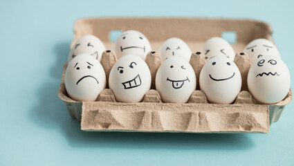 Eggs with funny and sad faces on blue background
