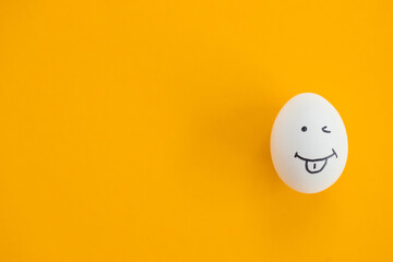 Egg with funny face on yellow background