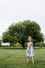 Obraz premium Happy emotional child girl posing outside in the green park. Fashion kid. Smiling toodler girl walking in park.