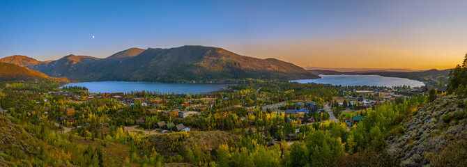 Fototapeta na wymiar Panoramic view of two Colorado lakes and towns next to them on fall evening with sun setting and moon rising