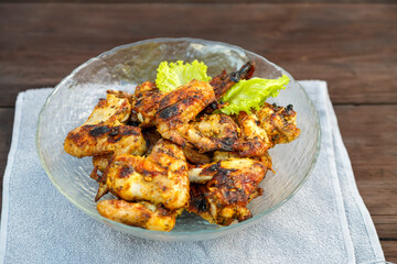 Chicken wings in a plate on a napkin on a wooden table.