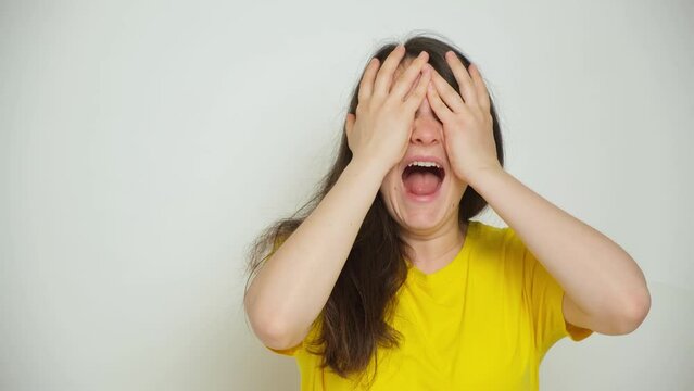 A woman dries her hair with a dryer, looks at her hair and covers her face with her hands screaming.