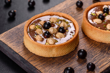 Delicious fresh nougat and nut tart with fresh berries on a wooden cutting board