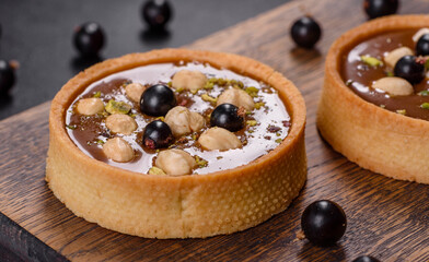 Delicious fresh nougat and nut tart with fresh berries on a wooden cutting board