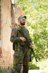 Portrait of a Ukrainian man with a weapon near a destroyed building