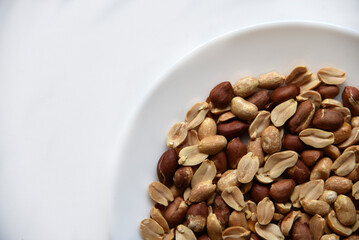 Fried delicious peanuts on a white plate close-up