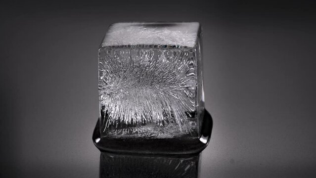 Melting ice cube. Cube starts spinning, rotating and leaves scene to foreground. 