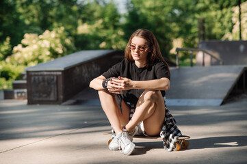 Fototapeta na wymiar Female skater with a skateboard relaxing in the skating rink