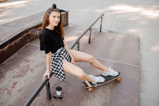 Female skater with a skateboard relaxing in the skating rink