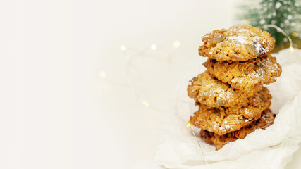 Christmas and New Year pastry. Homemade oatmeal cookies with seeds and cranberries. Winter holiday food banner with natural handmade cookies and holiday decoration on white background with copy space