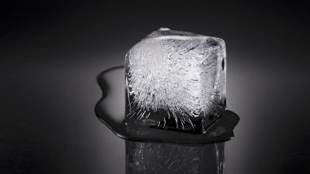 Melting ice cube, water flowing to background, later to foreground. 