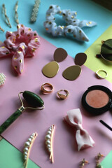 Various accessories, make up products and jewelry on various colorful pastel backgrounds. Selective focus.