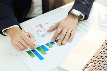Close-up of unrecognizable business analyst in formal suit sitting at table and comparing current profit with previous month while doing paperwork