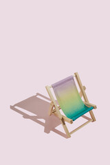 Mini colourful beach deck chair with sharp shadow against pink background. Creative summer concept with a copy space. Minimal relax and vacation idea.