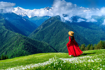 Tourist enjoy view of green pasture and flowers near snow mountain in Georgia. - obrazy, fototapety, plakaty