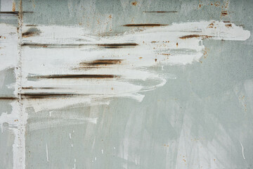 Scratches on a gray iron wall are carelessly smeared with white paint. There is a weld and rust appears. Grunge. Background. Texture.