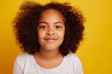 portrait of a young African girl smiling and rejoicing on a clean yellow background