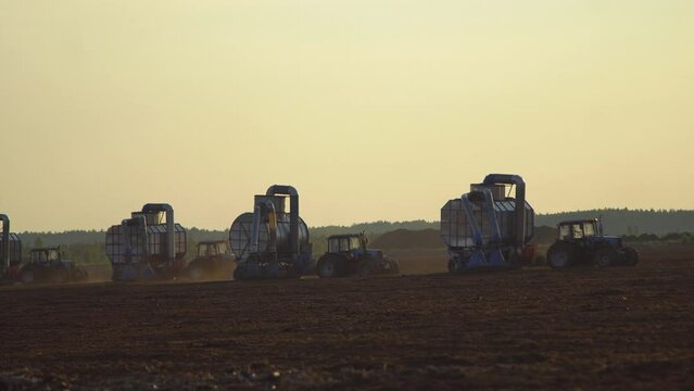 Peat harvester agricultural tractors on collecting extracting peat at sunset. Mining peatland.