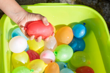 child hands holding colorful balloon water bombs