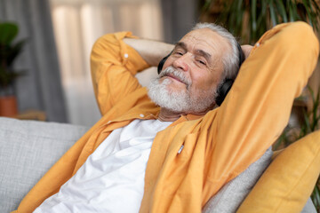 Good-looking elderly man enjoying newest wireless headset at home