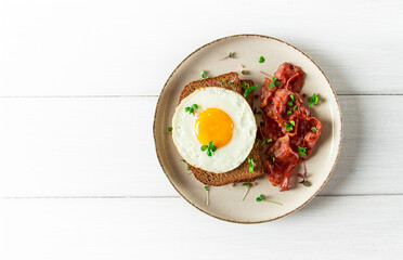 Breakfast, fried egg with bacon, micro-green, on a light background, no people, selective focus,