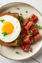 Breakfast, fried egg with bacon, micro-green, on a light background, no people, selective focus,